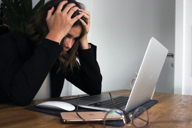 A woman is stressed out looking at her laptop because of her lack of sleep