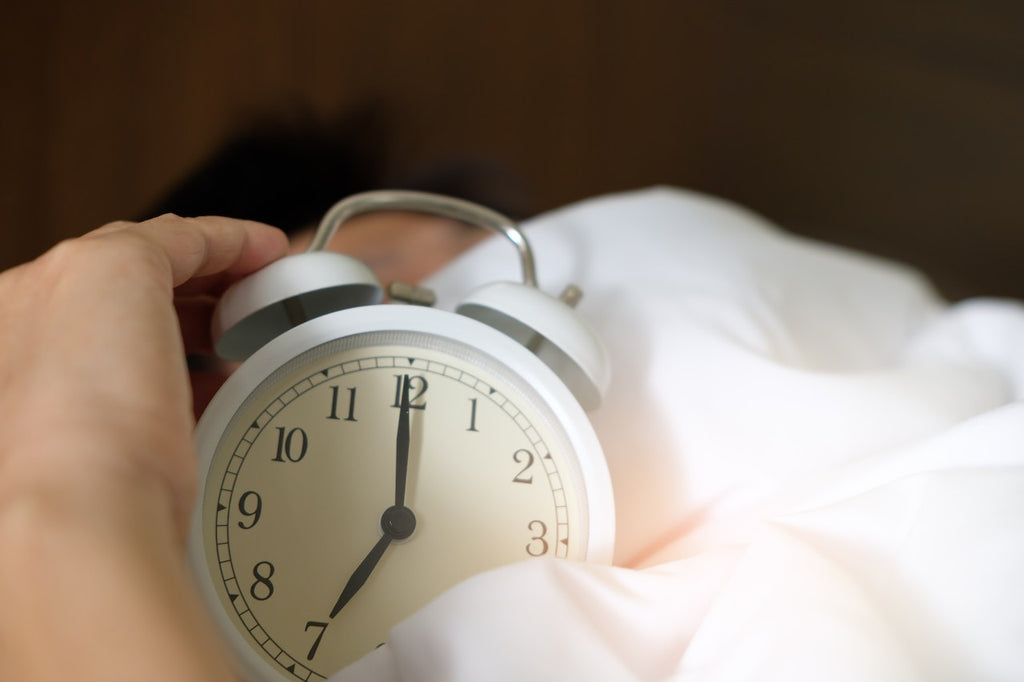 A sleeping person reaches for his alarm clock